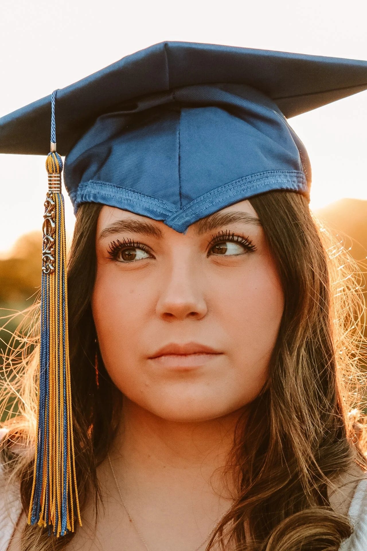 Close portrait of a graduate in a blue cap at golden hour