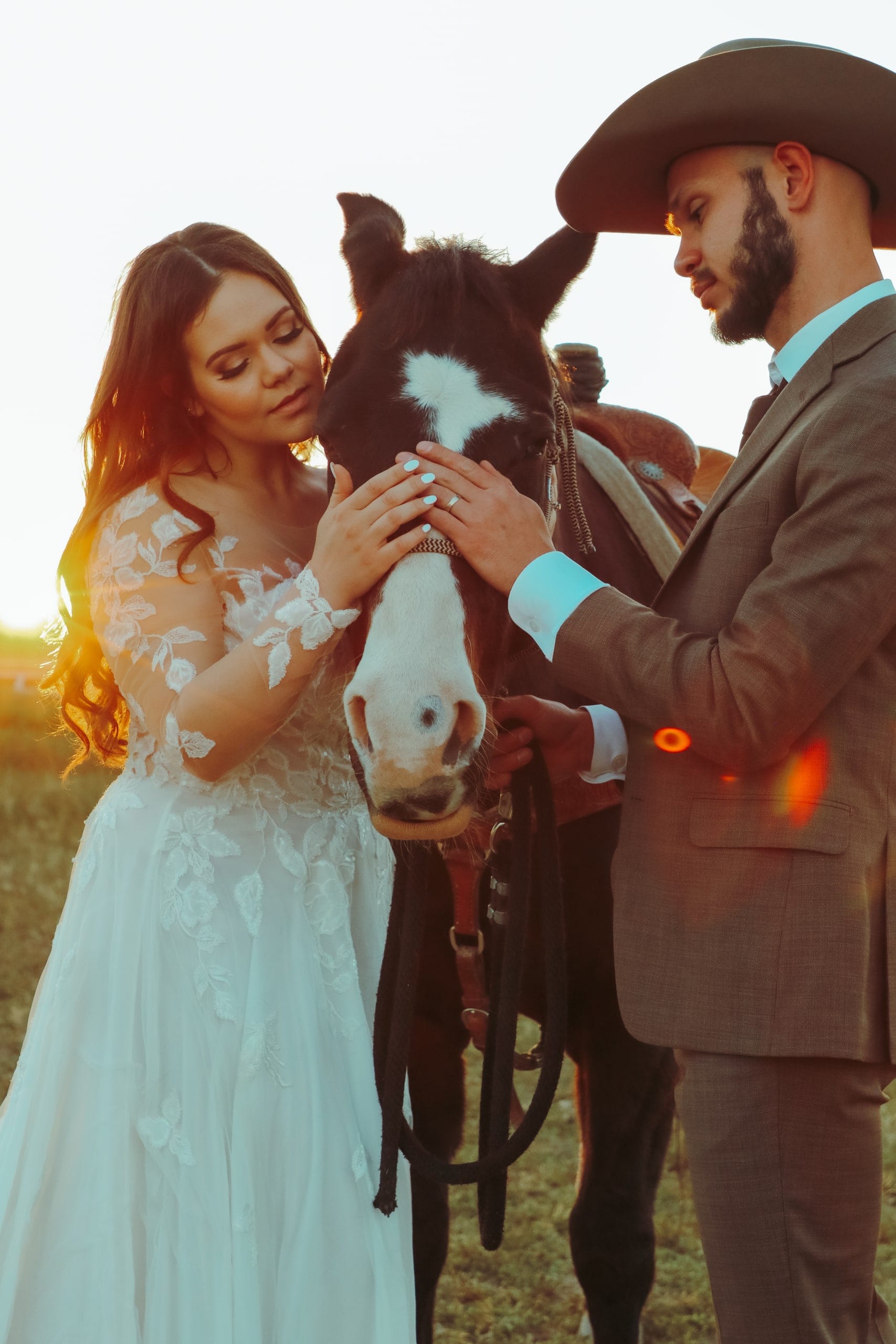 Bride and groom in a cowboy hat with their horse at golden hour